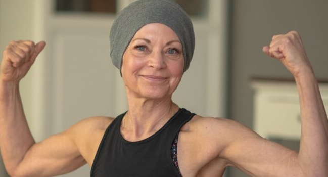 Female cancer survivor flexes muscles